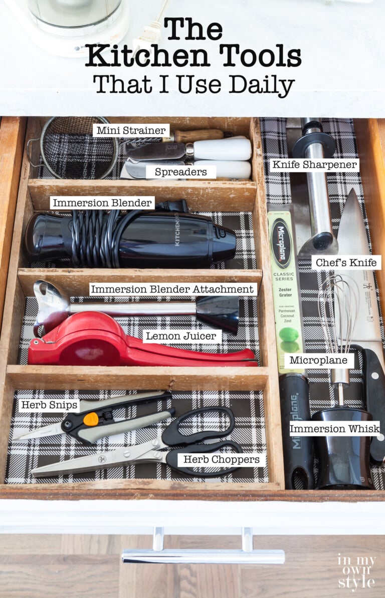 Open kitchen drawer showing all the tools inside. Text overlay says what each item is - Mini Strainer Spreaders, Knife Sharpener, Immersion Blender, Chef's Knife, Microplane, Herb Snips