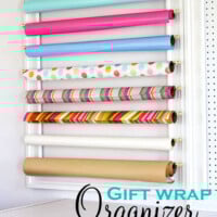 Gift wrap rolls organized on a wall in a frame. Overlay says Gift Wrap Organizer