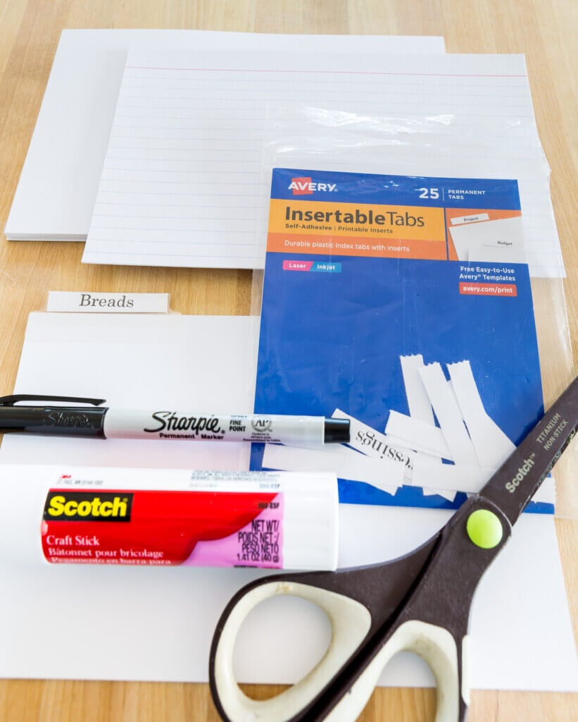 Supplies needed to fill and organize a new recipe card box. Glue stick, Sharpie, Scissors, Index cards and divider tabs.