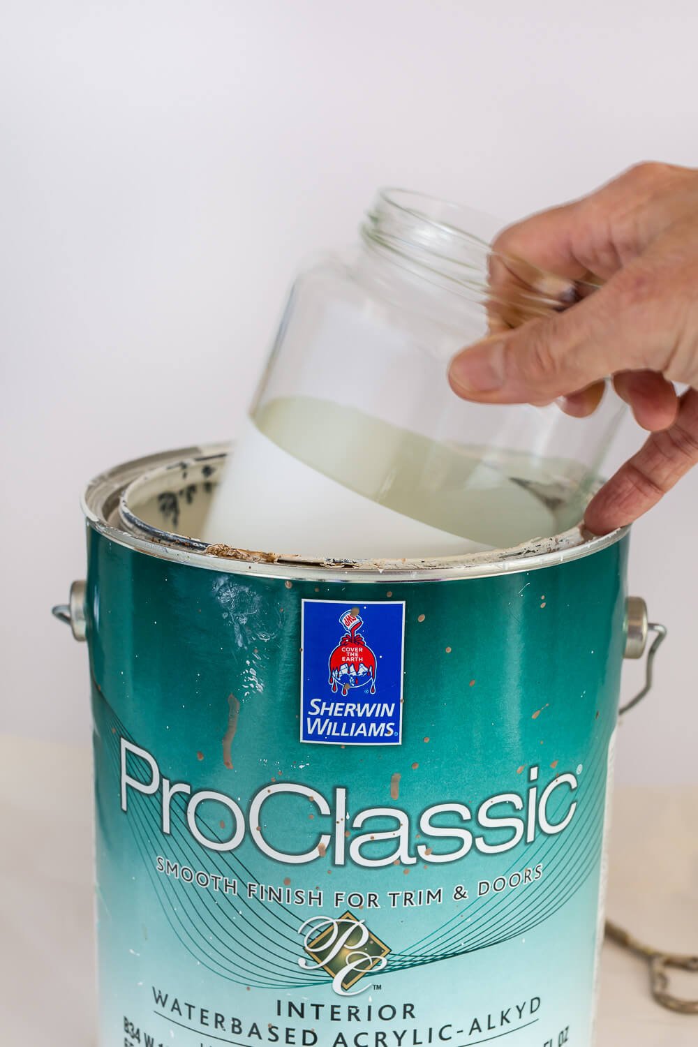 How to dip a glass jar into a can of paint to create a white dipped glass vase.