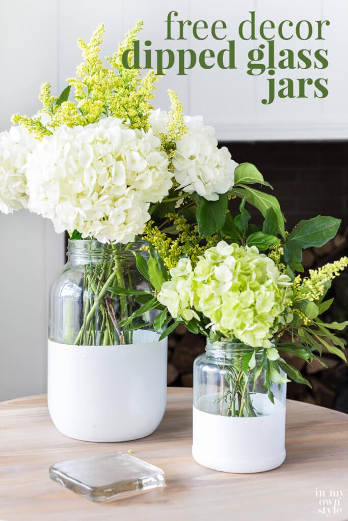 Two glass vases with white painted bottoms filed with white and light green flowers.