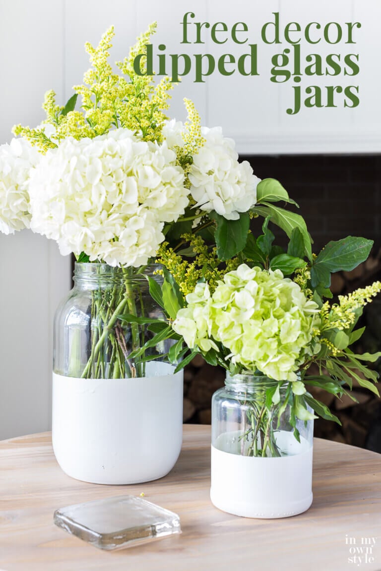 Two glass vases with white painted bottoms filed with white and light green flowers. Text overlay says free decor dipped glass jars.