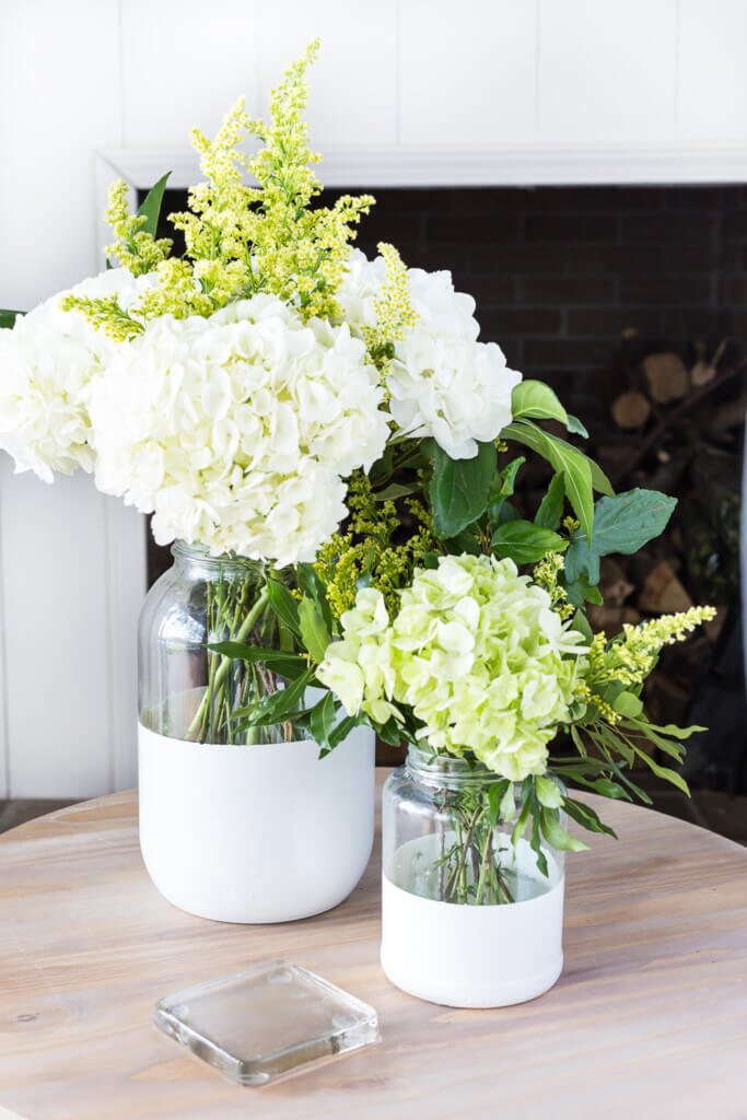 Large clear glass jars turned into dipped paint vases. Placed on a table creates budget friendly decorating style.