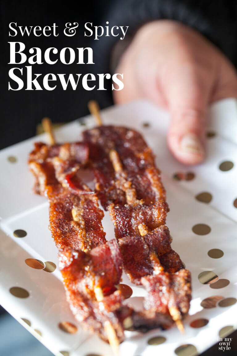 Sweet and spicy bacon on skewers on a white plate with gold dots. Text overlay says Sweet & Spicy Bacon Skewers