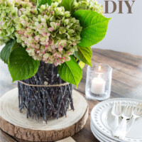 Twig vase on a tree trunk slice on a dining table. Text overlay says Fall Vase DIY