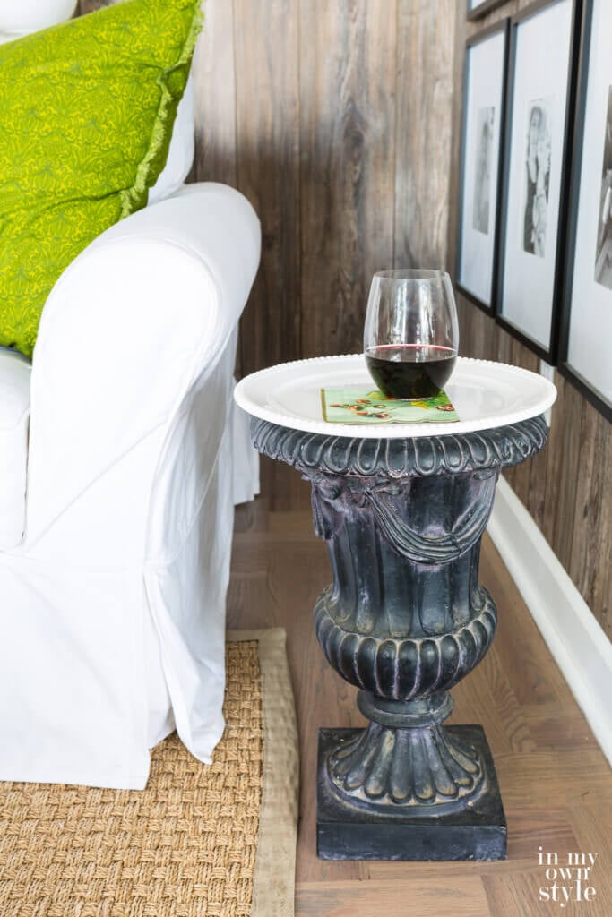 Black garden urn repurposed into a end table using a cake plate.