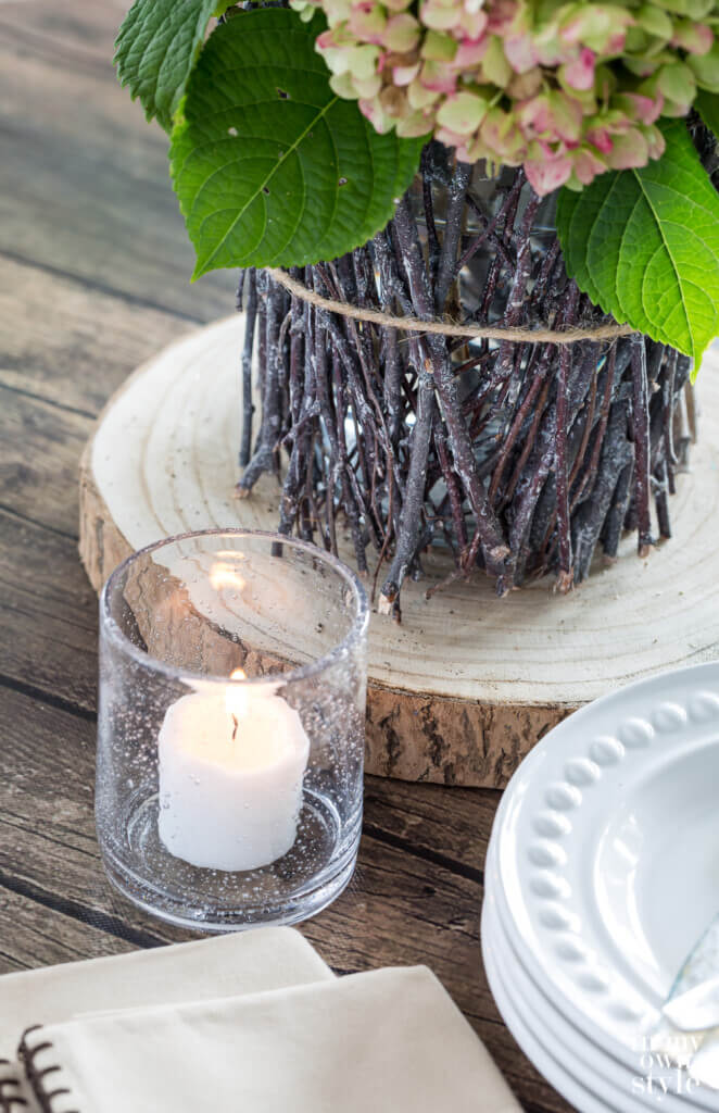 Dining table decorated for fall using a twig vase and seeded glass candle holder.
