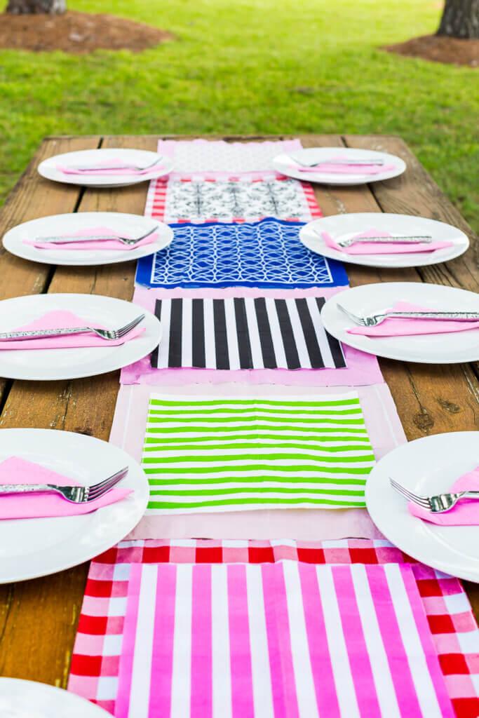 Colorful patterned paper napkin runner on wood picnic table on lawn.
