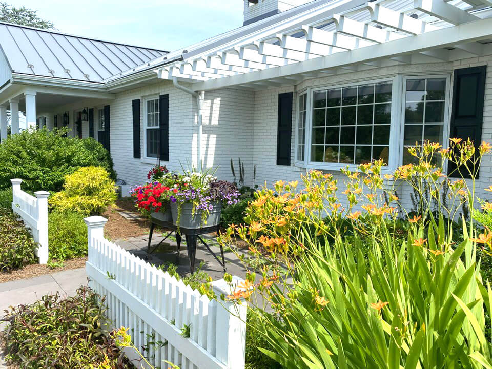 Back of ranch house after makeover. Painted white, pergola added and slate walkway.