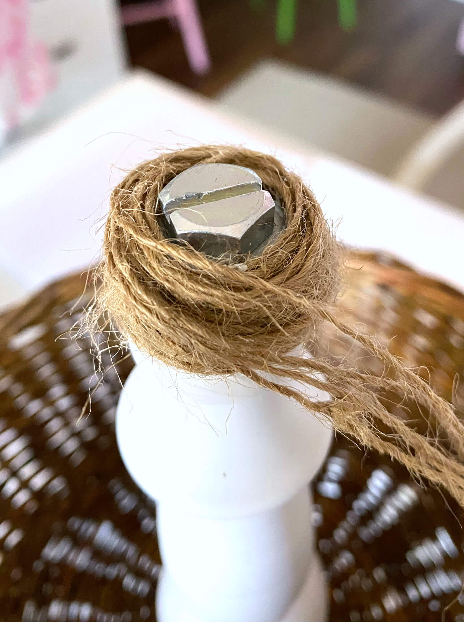 Wrapping twine around screw and washer on the top of a tiered produce storage basket for a kitchen counter.