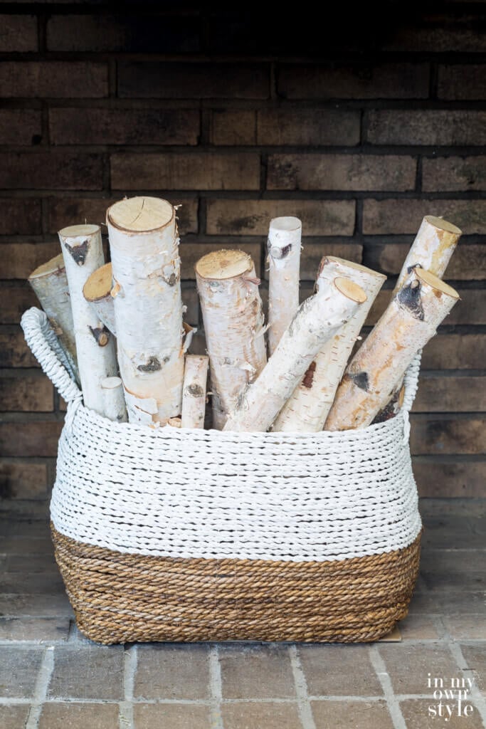 Bundle of Birch logs in a large basket in a fireplace.