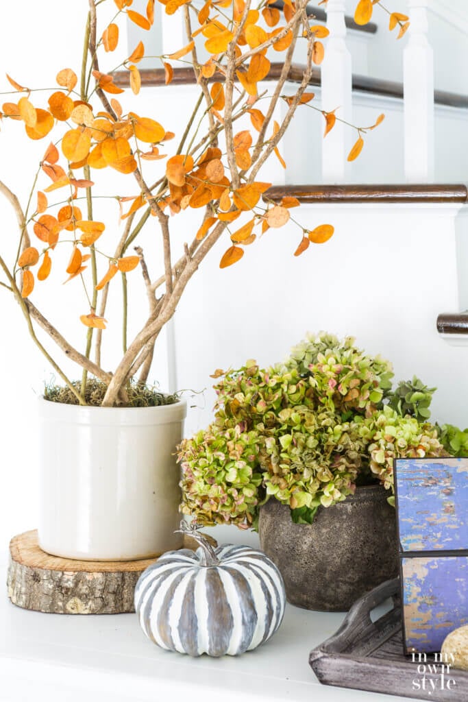 Natural elements create fall decor on a white entryway sideboard.