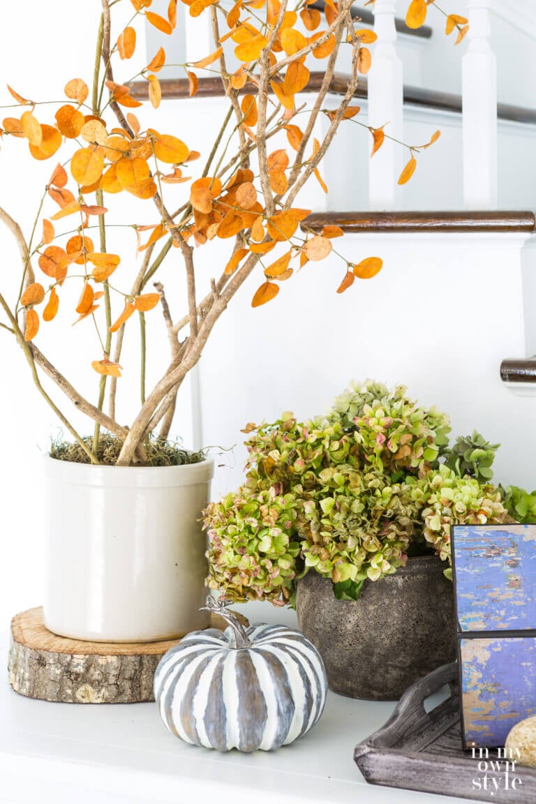 Natural elements create fall decor on a white entryway sideboard.