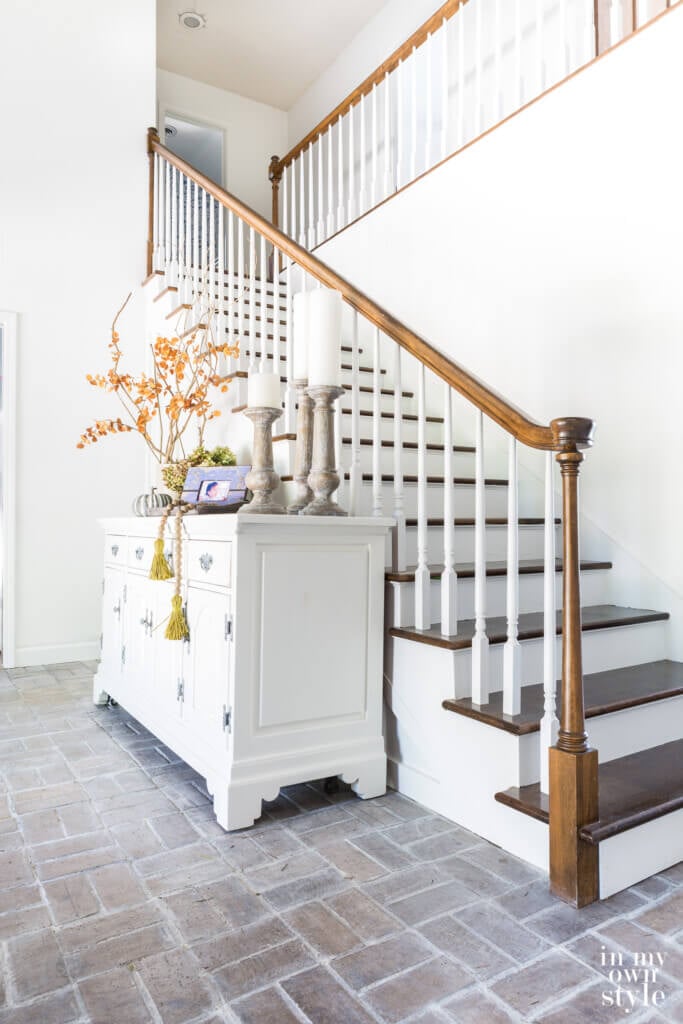 White sideboard decorated for fall in two story entry. 