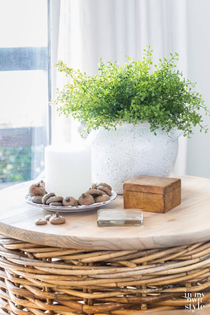 Round wicker table with fall decor in the colors green and white.