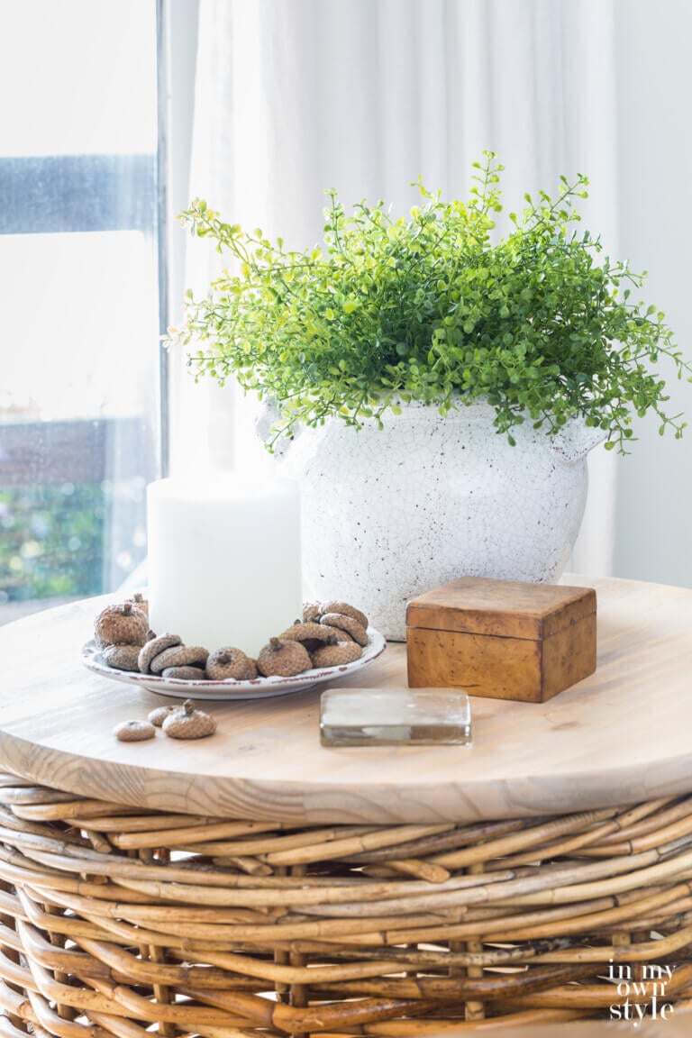 Round wicker table with fall decor in the colors green and white.