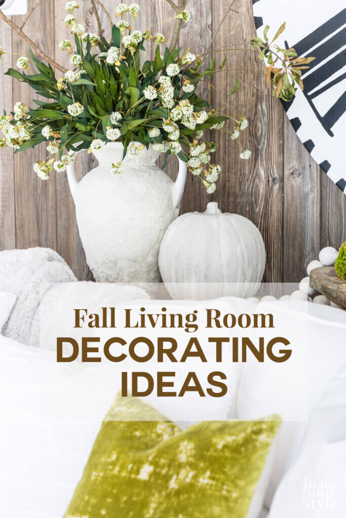 A stone vase and pumpkin on a sofa table with faux barn wood paneling behind them. Text says Fall Living Room Decorating Ideas