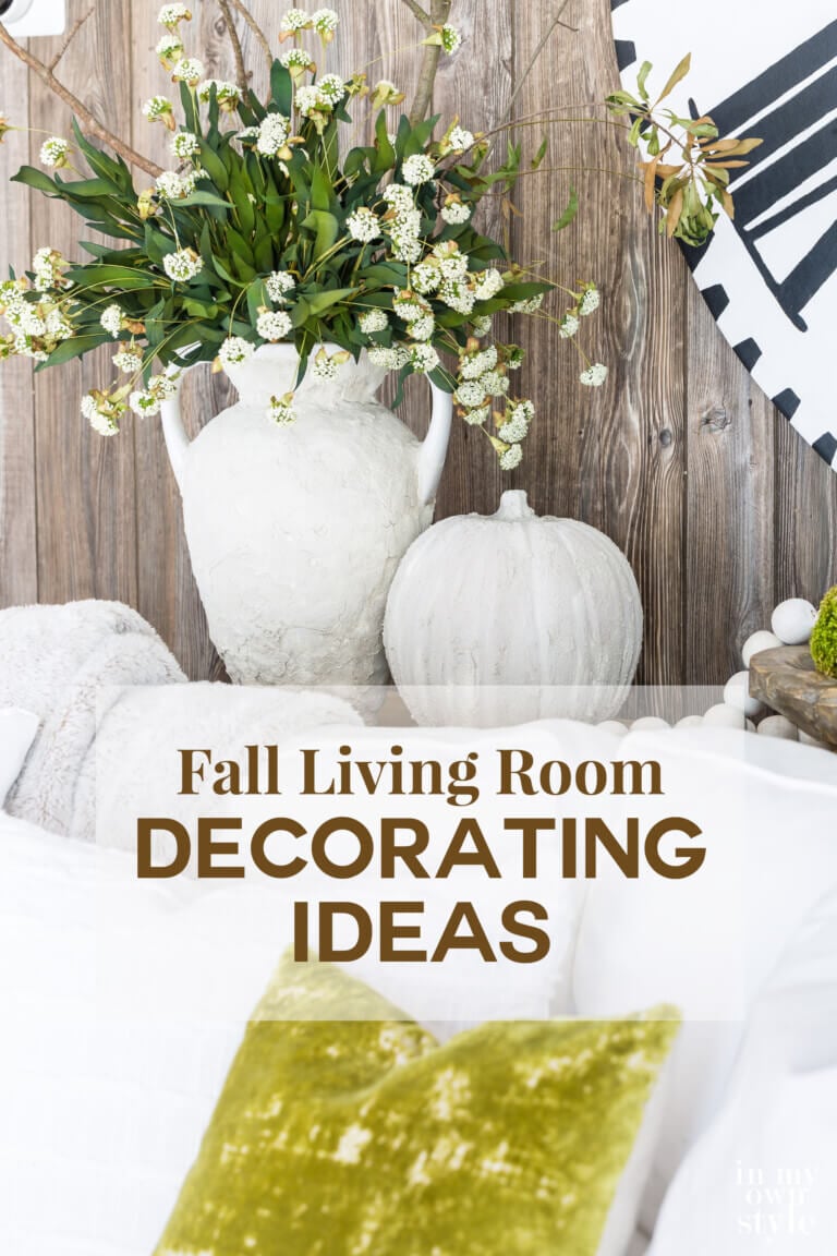 A stone vase and pumpkin on a sofa table with faux barn wood paneling behind them. Text says Fall Living Room Decorating Ideas