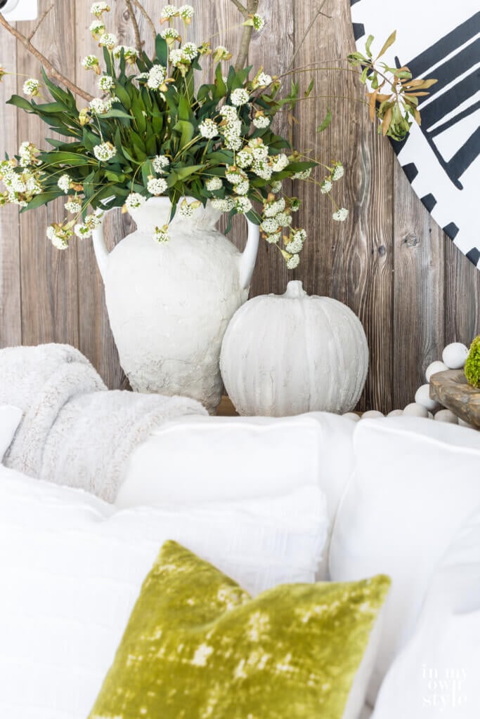 Fall vase ideas using Plaster to cover a chipped vase and plastic pumpkin. Displayed on a console table behind a sofa. 