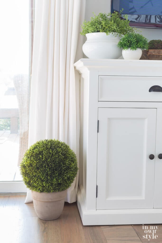 Green moss globe on floor in whitewashed terracotta pot.