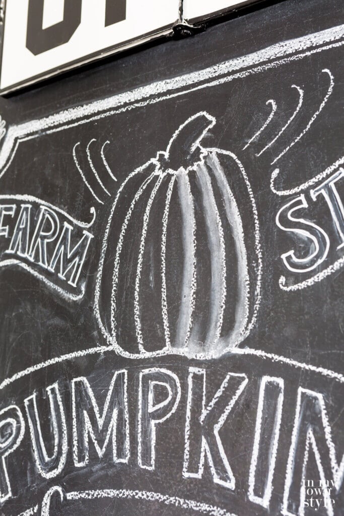 Close up of chalk lettering and pumpkin drawing on chalkboard wall.