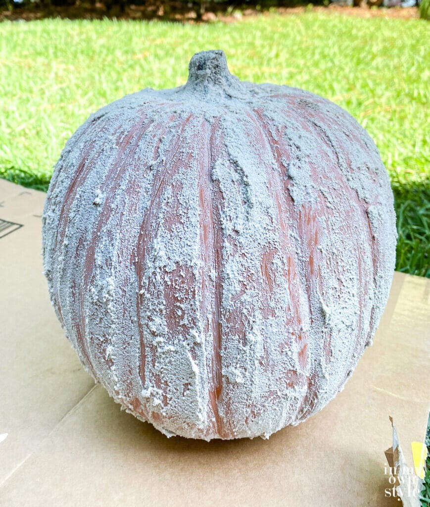 Close up of fake pumpkin getting a textured aged concrete look.