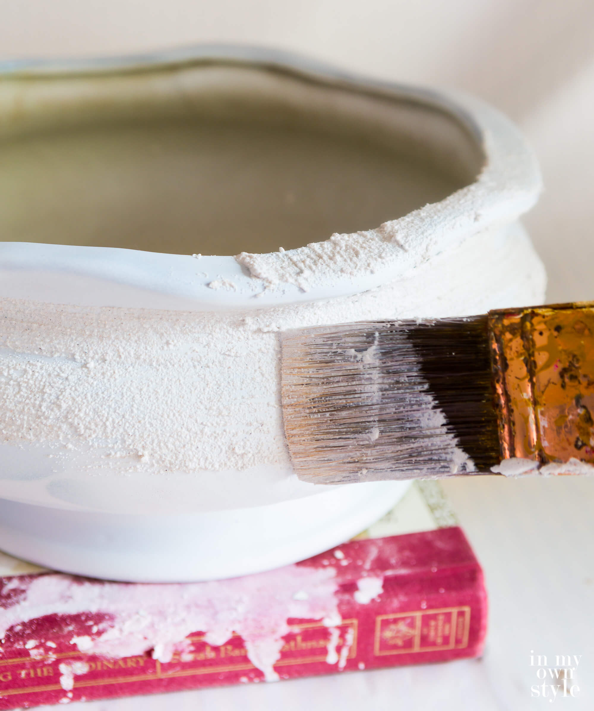Brushing on stucco patch to create texture on a ceramic planter.