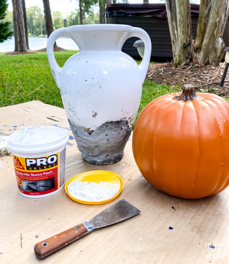 Large chipped white urn and plastic pumpkin before getting the look of DIY aged concrete.