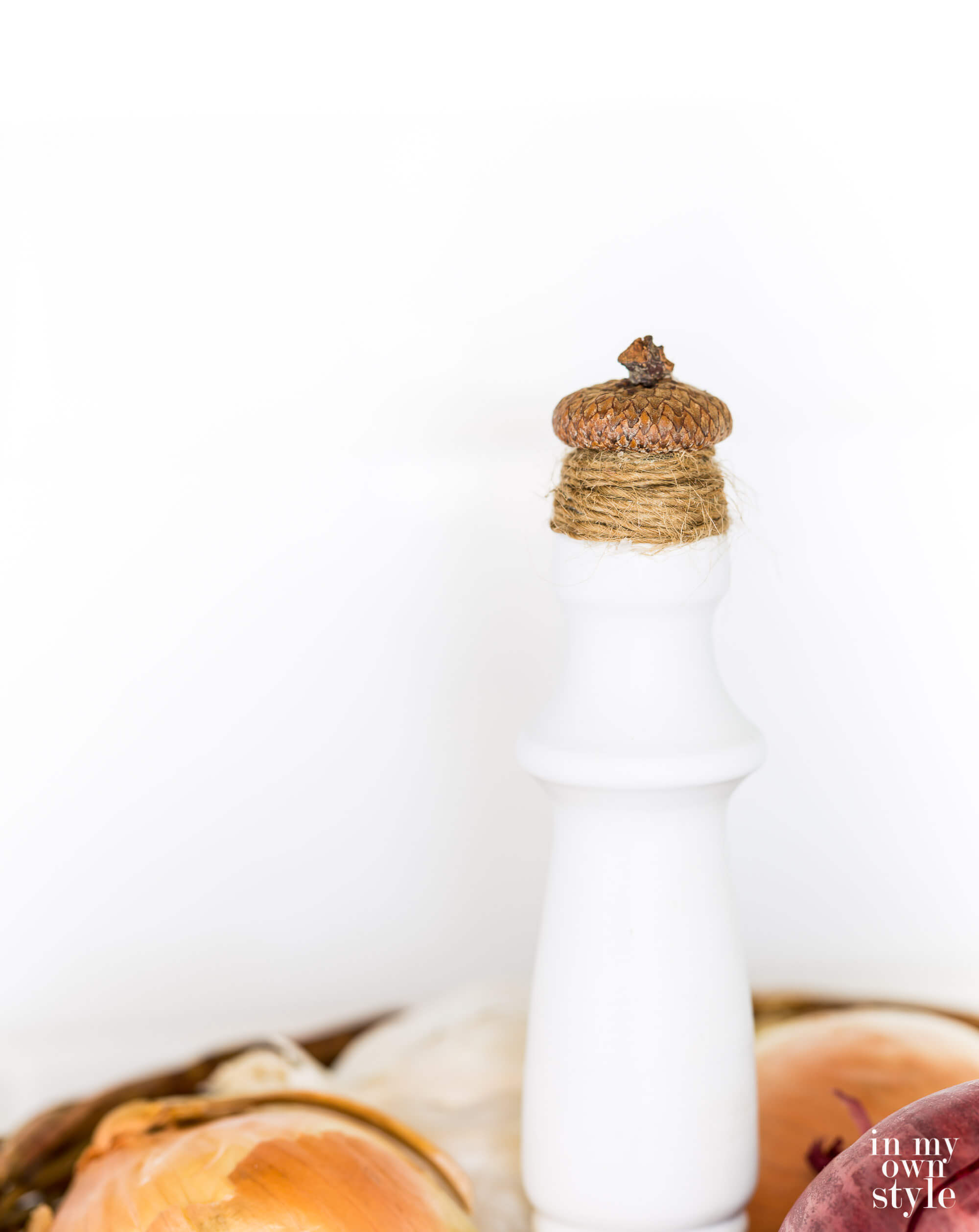 Close up of finished acorn and twine finial on top of a 2 tiered countertop fruit basket.