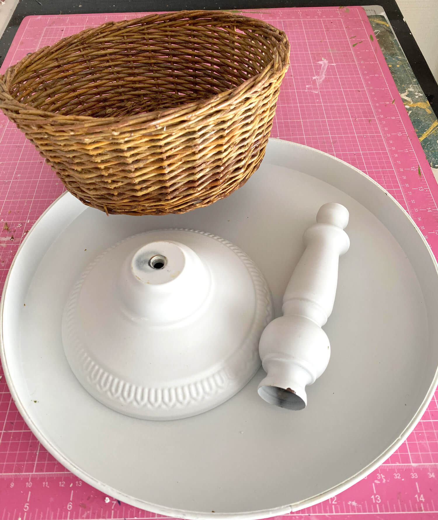 One section of 3 tiered kitchen stand with base, rod and a round wicker basket.