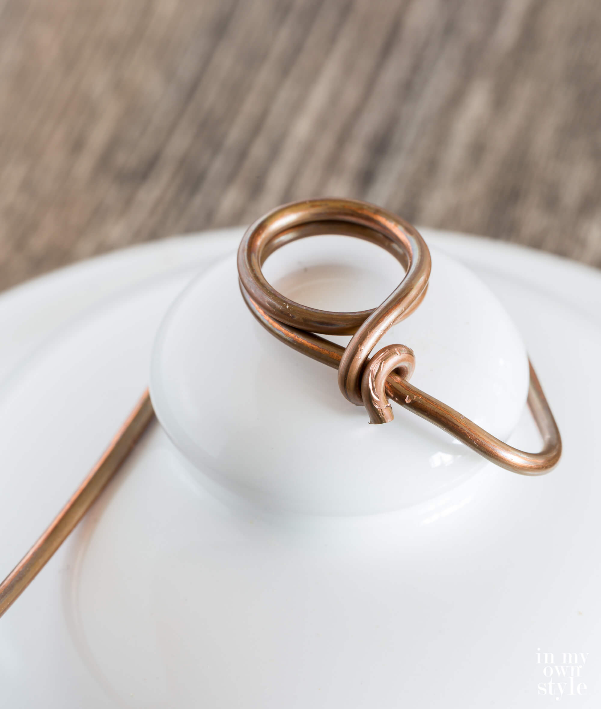 Bending wire to ceramic jar top to make a photo holder.
