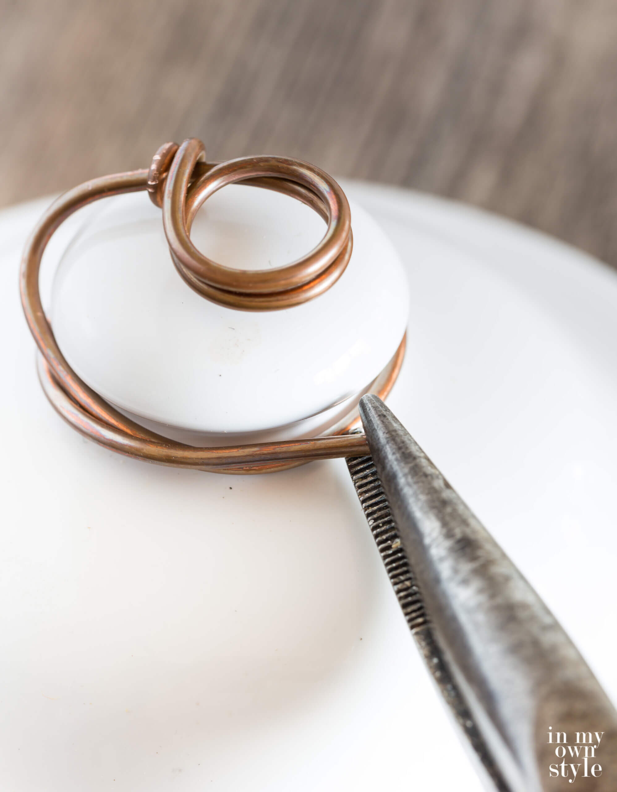 Attaching wire to ceramic jar top to make a photo holder.