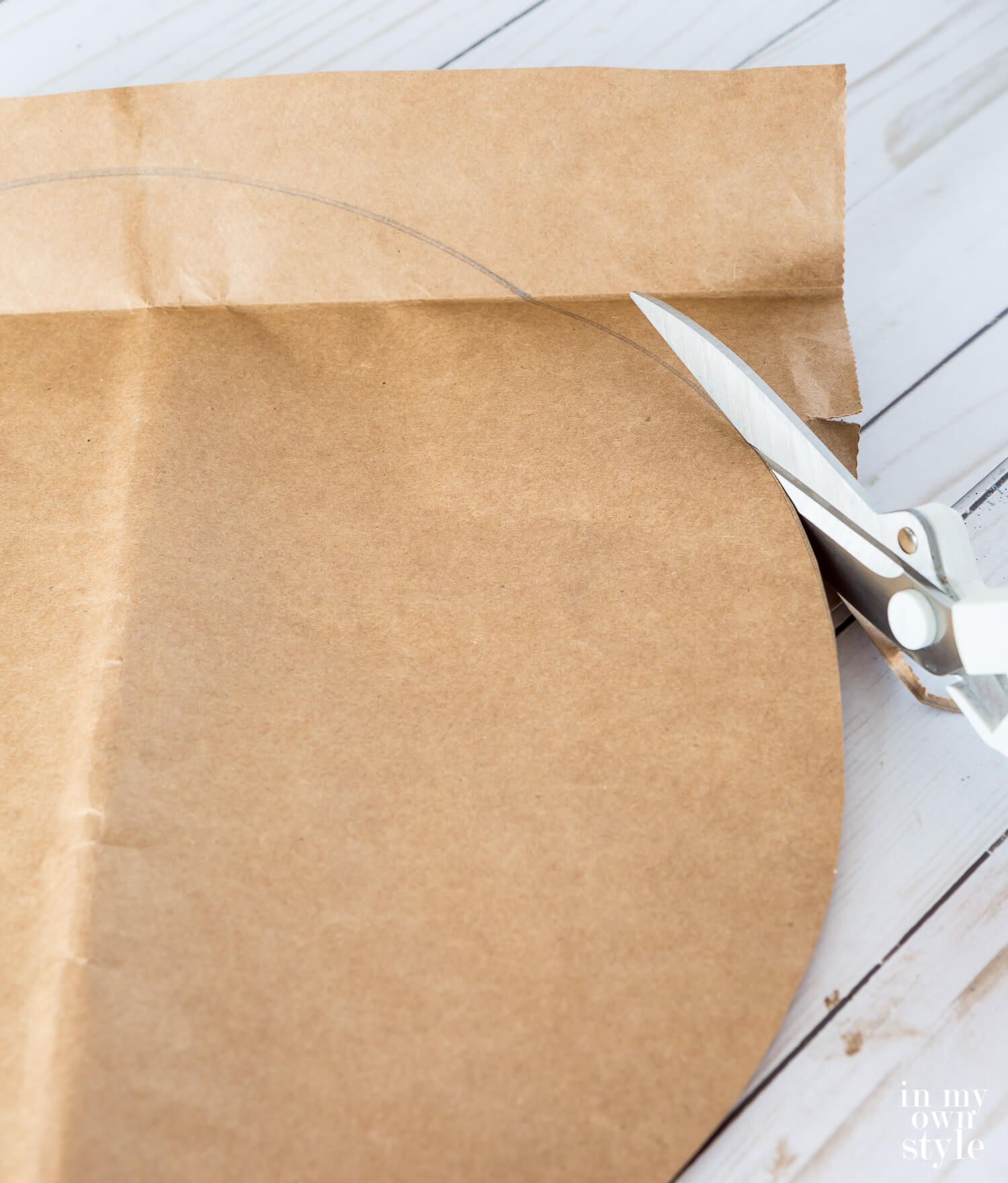 Cutting a large circle from a brown paper grocery bag.