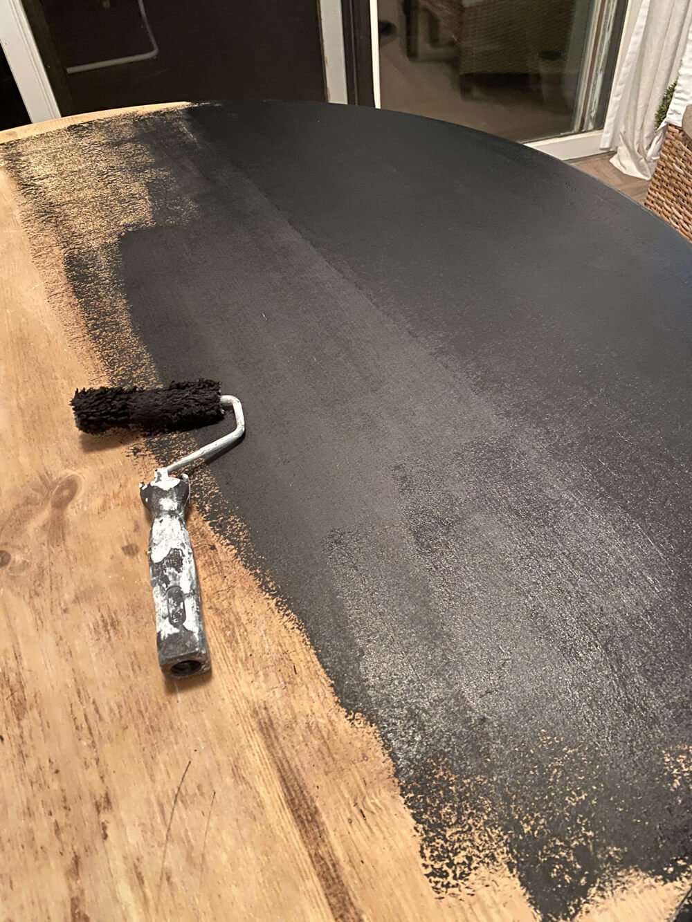In the process of paint a round wood dining table with black base coat layer.