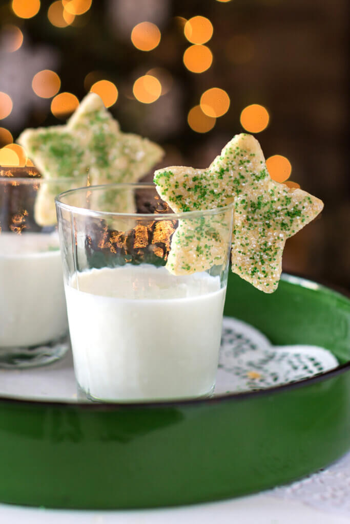 2 star Christmas cookies on the rims of glasses of milk.