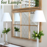 Two tall buffet style lamps of sideboard in foyer. Text overlay says Christmas decorating for Lamps