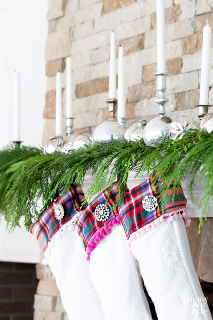 White Plaid trimmed Christmas stockings hanging from a fireplace mantel.
