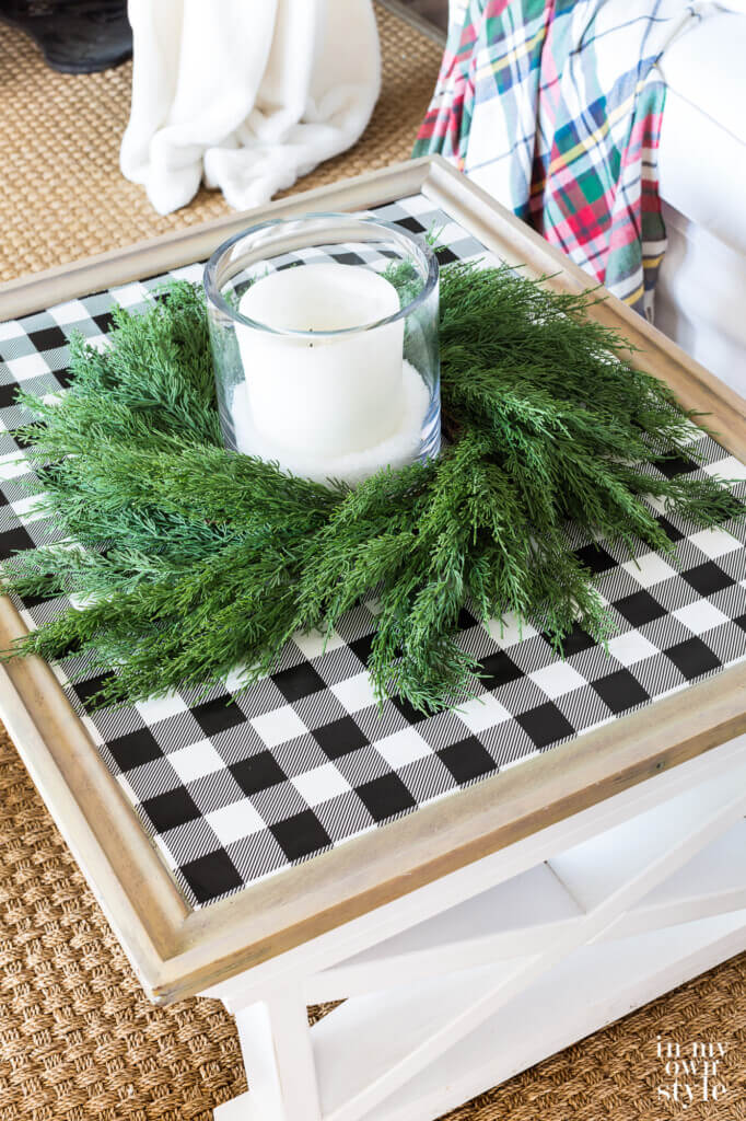 Farmhouse coffee table decorated for Christmas with black and white checked gift wrap on table top with cedar wreath and candle.