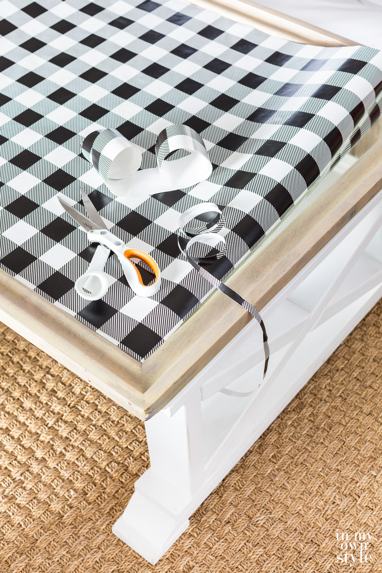 Black and white check gift wrap being cut to fit table top.
