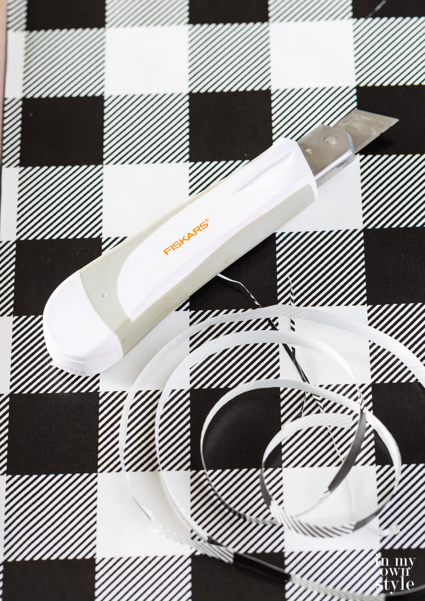 Fiskars craft knife on black and white check gift wrap.