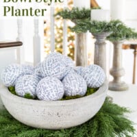 Large faux cement bowl on a wreath on a sideboard. Text overlay says DIY large faux stone bowl style planter.