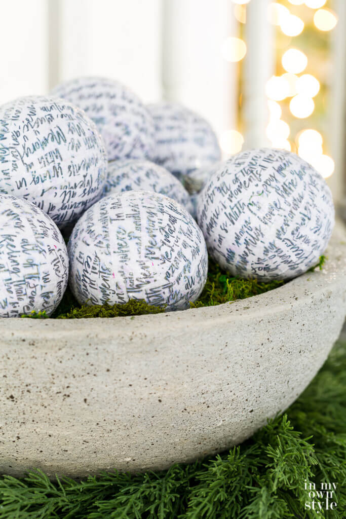 DIY faux large cast stone planter bowl filled with white glittered Christmas ornaments.