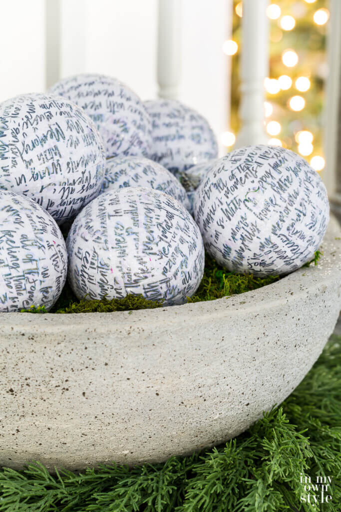 DIY faux large cast stone planter bowl filled with white glittered Christmas ornaments.