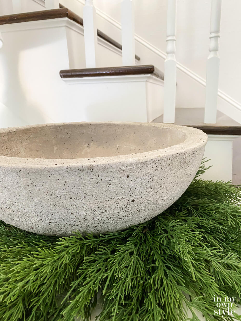 Close up shot of finished fake concrete bowl planter. It is placed on a wreath on a sideboard.