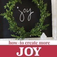 Christmas wreath hung on chalkboard. Text overlay says how to create more joy this Christmas