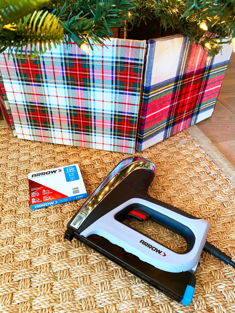 Plaid DIY tree collar with Arrow staple gun and staples on the floor nearby.