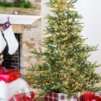 Living room with Christmas tree that has a plaid fabric wrapped frame tree collar around the stand.