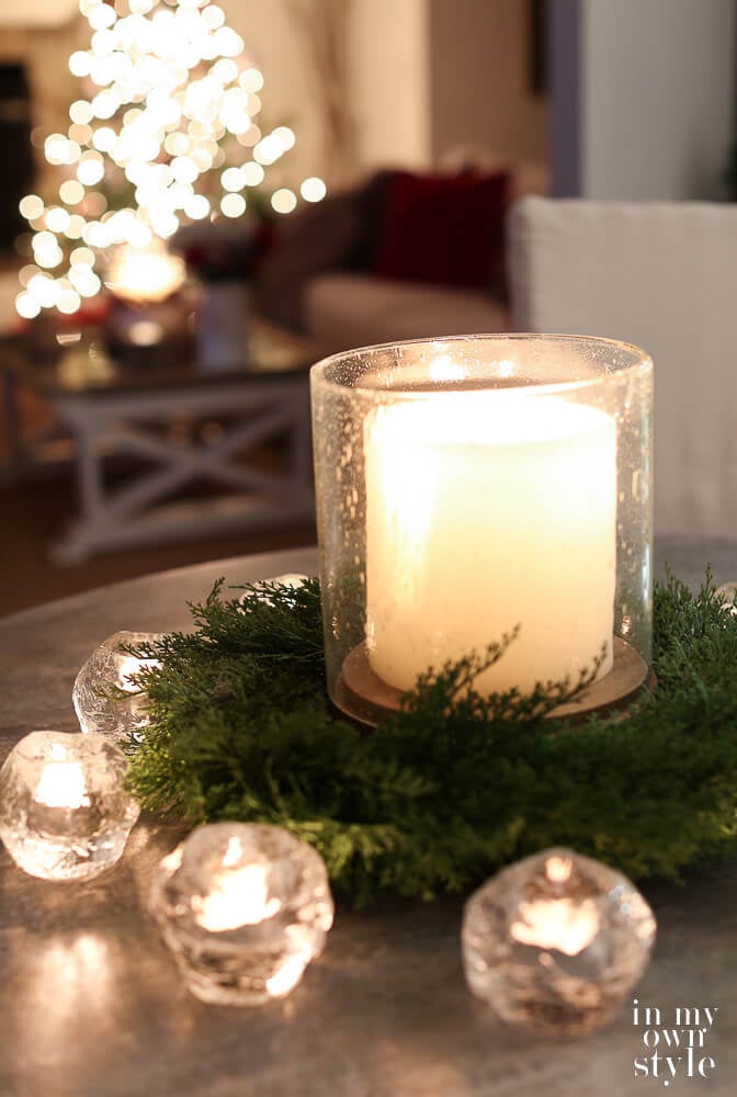 Candle on table with Christmas tree in the background
