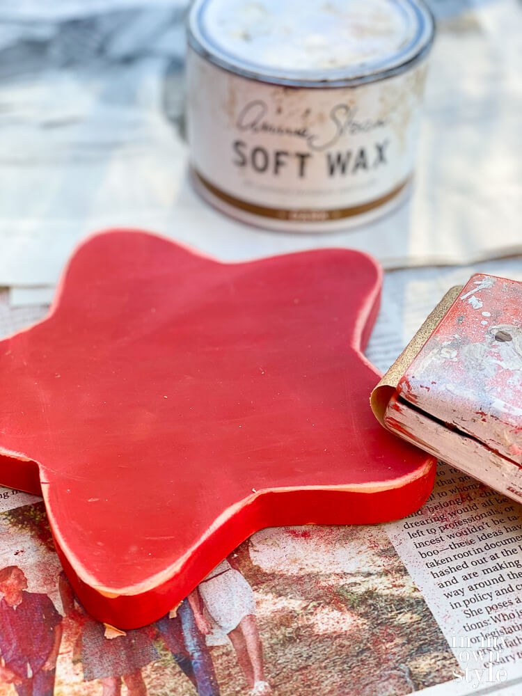 Painting a wood star red and sanding it.