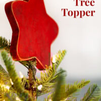 Rustic red wood star Christmas tree topper on tree. Text overlay on image says DIY Christmas tree topper.